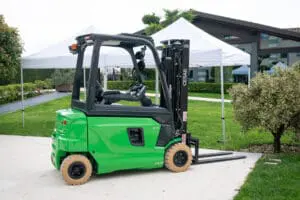 Green CESAB B420 forklift in use in a warehouse full of stacked cardboard, seen from rear view. - Prince Maasdijk