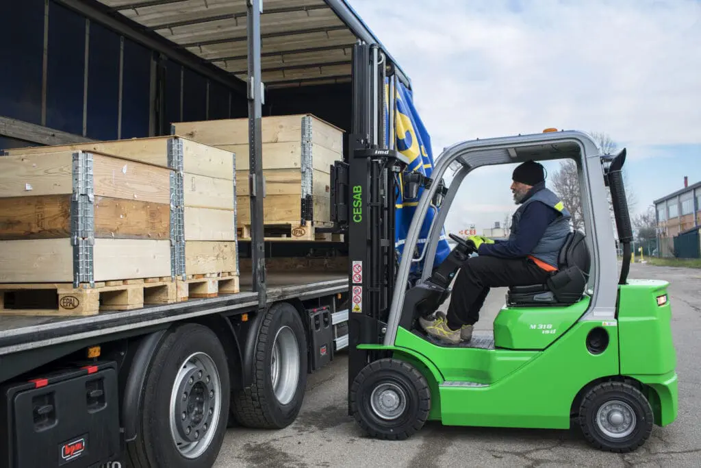 Driver on a green CESAB M318 forklift loading wooden boxes onto a truck. - Prince Maasdijk