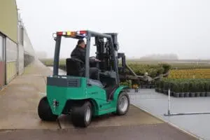 Driver on a green Prince Panther XL-E Zero Emission forklift in use at a nursery in foggy weather. - Prince Maasdijk