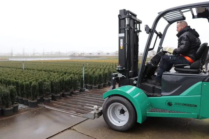 Driver on a green Prince Tiger XXL-E Zero Emission forklift picking up plants at an outdoor site. - Prince Maasdijk