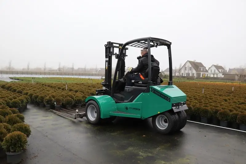 Driver on a green Prins Tiger XXL-E Zero Emission forklift in use on an outdoor nursery of potted plants. - Prince Maasdijk
